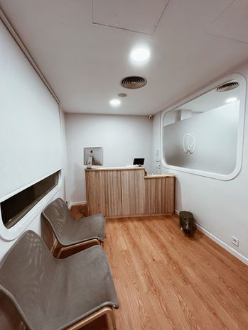 Sala de espera de la clínica, con bancos de madera y la cristalera del logo