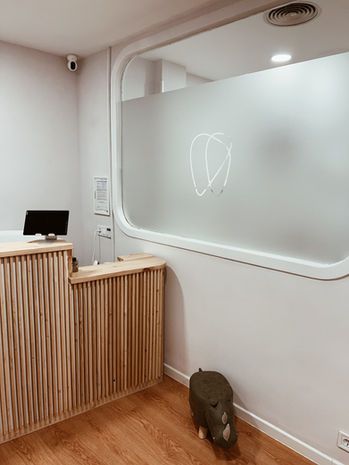 Recepción de la Clínica Dental Aravaca, con la cristalera del logo